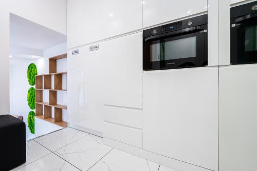 cocina con paredes blancas y electrodomésticos negros en BioKompas SPA Apartment, en Wroclaw