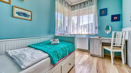 a room with a bed with a desk and a chair at Apartament Lazurowy - 5D Apartamenty in Świeradów-Zdrój