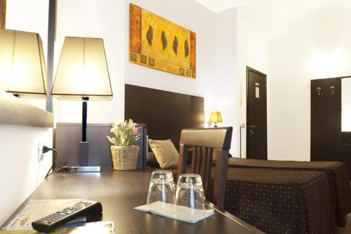 羅馬的住宿－羅馬度假村酒店，客房设有一张桌子、一张沙发和一张带遥控器的桌子。