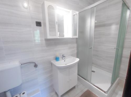 a white bathroom with a sink and a shower at Viktória Panzió Zamárdi in Zamárdi