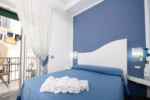 a bedroom with a blue bed with white shoes on it at La Magnolia Rooms in Procida