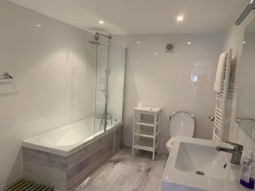 a bathroom with a tub and a toilet and a sink at La Cour des Cloches in Mainxe