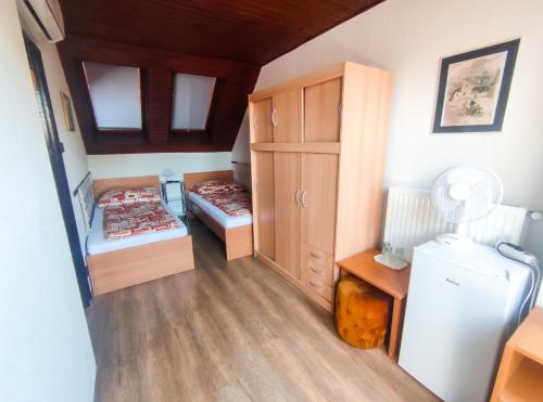 a small room with two beds and a refrigerator at Viktória Panzió Zamárdi in Zamárdi