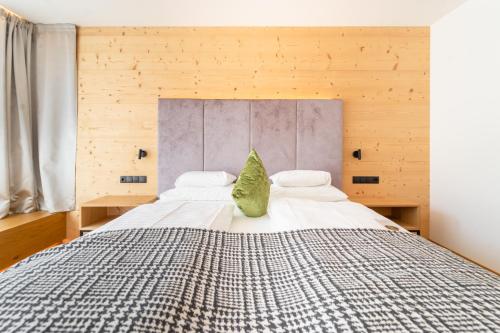 a bedroom with a large bed with a green pillow at Hotel Störes - Living Nature Hotel in San Cassiano