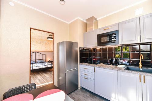 a kitchen with white cabinets and a stainless steel refrigerator at Dzintari in Ventspils