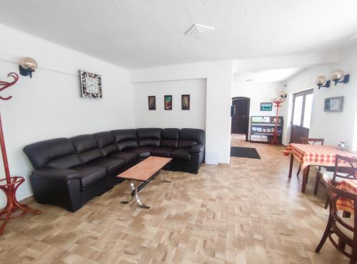 a living room with a black leather couch and a table at Viktória Panzió Zamárdi in Zamárdi