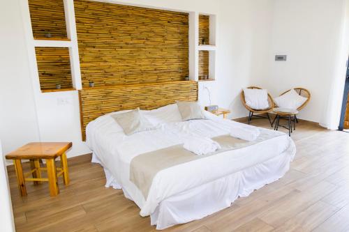 a bedroom with a large white bed and two chairs at Résidence de la Plage in Porto-Vecchio