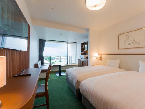 a hotel room with two beds and a desk and a window at Rakuten STAY Atami in Atami