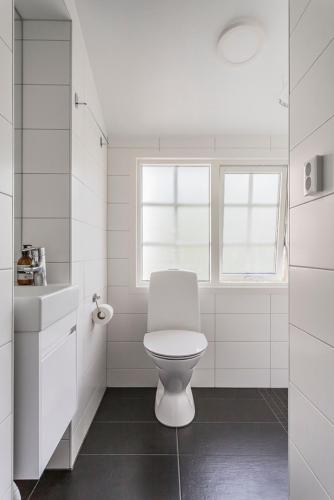 a white bathroom with a toilet and a window at Hotell MAVI in Viken