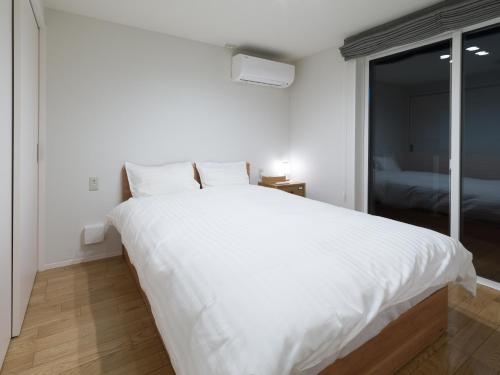 duże białe łóżko w pokoju z oknem w obiekcie Rakuten STAY HOUSE x WILL STYLE Hagi Nishitamachi w mieście Hagi