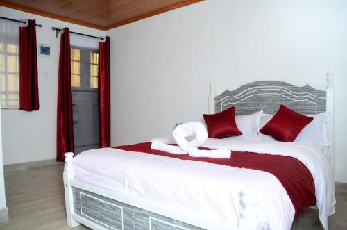a bedroom with a large white bed with red pillows at Jazby Guest House, Naivasha in Naivasha