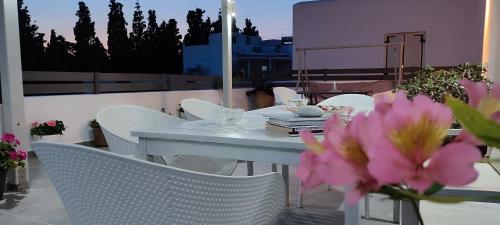 una mesa y sillas en un balcón con flores rosas en Maria Studios, en Parikia