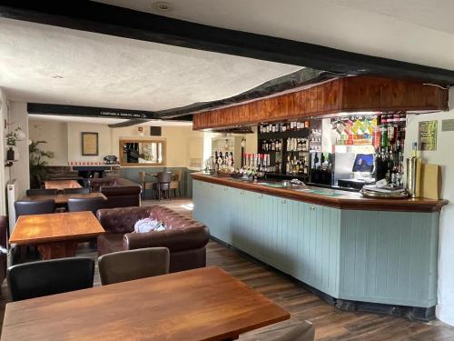 a bar in a restaurant with tables and chairs at The Maltsters Country Inn in Badby