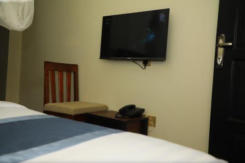 a bedroom with a bed and a flat screen tv on the wall at Galaxy Motel Kampala in Kampala
