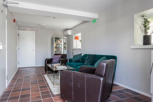 a living room with a green couch and chairs at Hotell MAVI in Viken