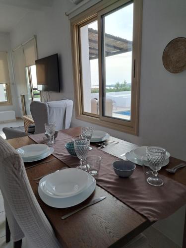 a wooden table with plates and glasses on it at Villa Enalia Paphos in Paphos City
