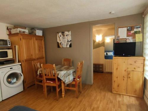 une cuisine avec une table et des chaises et un micro-ondes dans l'établissement Appartement T2 bis avec cour, proche télécabine et commerces - Cauterets, 6 couchages - FR-1-234-127, à Cauterets