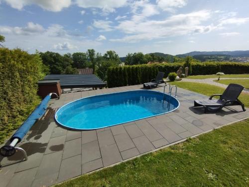 a swimming pool in a yard with two lawn chairs and a swimming poolitures at Vila Albrecht Vimperk in Vimperk