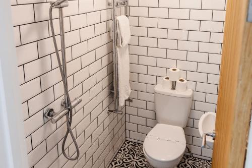 a white tiled bathroom with a toilet and a shower at 203, THE KOVÉ, West Hill Road in Bournemouth