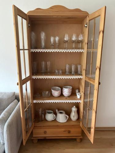 a wooden cabinet filled with dishes and glasses at Haus Schmetterling in Alpbach