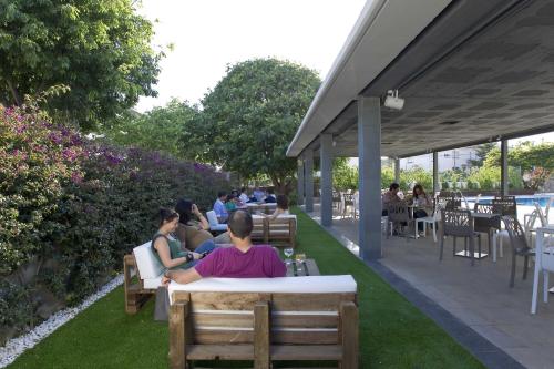 a group of people sitting at tables in a garden at Altafulla Mar Hotel in Altafulla