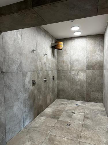 a large shower room with concrete walls at La Riva Mia Spa Dziwnów in Dziwnów