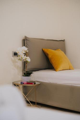 a bed with a yellow pillow and a table with flowers at Il Meraviglioso Mondo di Amélie in Agrigento