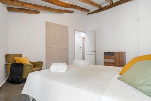 a white bedroom with a bed and a chair at El racó de les escales in Tivissa