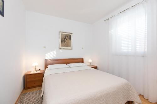 ein weißes Schlafzimmer mit einem Bett und einem Fenster in der Unterkunft Apartments Bella Vista in Krk