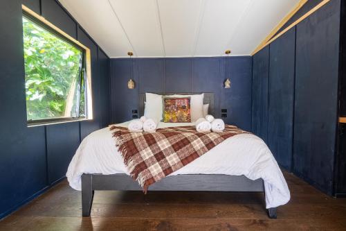 a bedroom with blue walls and a bed with two towels at The Urban Tramping Hut in Rotorua