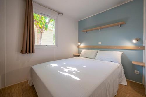 a bedroom with a large white bed with a window at Camping La Masia in Blanes