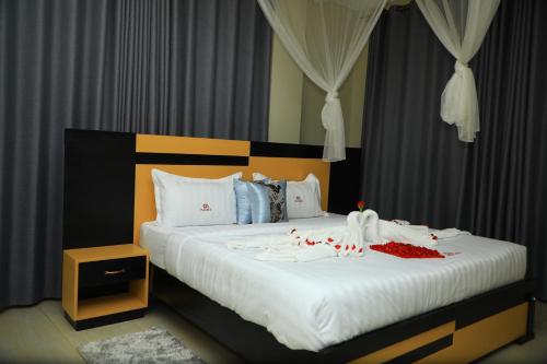 Un dormitorio con una gran cama blanca con adornos. en Galaxy Motel Kampala en Kampala