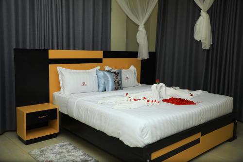 ein großes Bett mit weißer Bettwäsche und roten Dekorationen darauf in der Unterkunft Galaxy Motel Kampala in Kampala