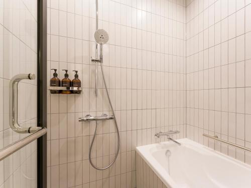 a white tiled bathroom with a shower and a sink at Rakuten STAY Atami in Atami