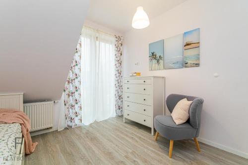 a bedroom with a bed and a chair and a dresser at Flatbook Apartamenty - Mikoszewo Wczasowa I in Mikoszewo