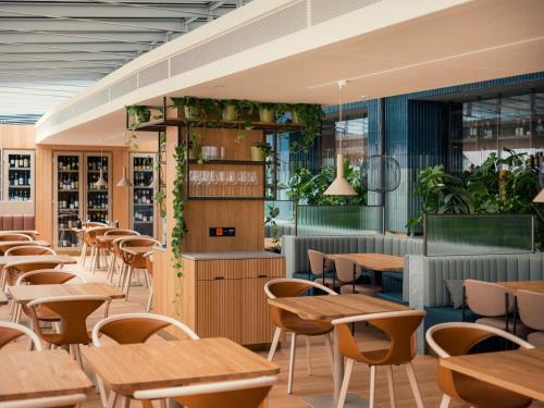 un restaurante con mesas de madera, sillas y plantas en Swissôtel Kursaal Bern, en Berna