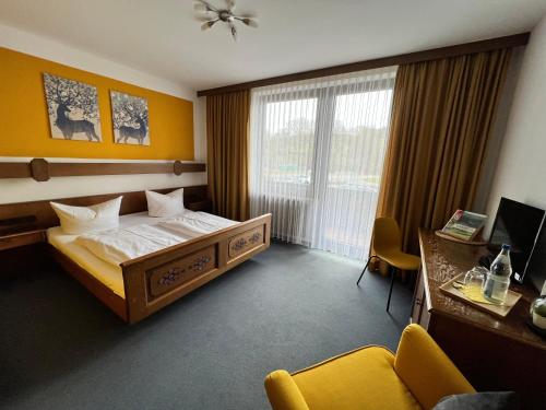 a hotel room with a bed and a desk and window at Hotelgasthof Schmucker in Mossautal