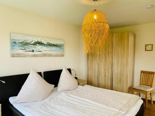 a bedroom with a bed with white sheets and a chandelier at FeWo PANORAMADECK Familien-strandnah-Garten-Hunde-Sport-und Schwimmbadnah-HansaPark in Sierksdorf