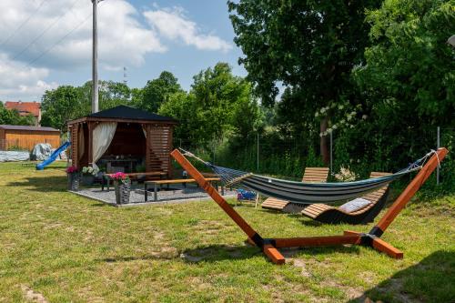 a hammock and chairs in a yard with a cabin at Apartamenty Pod Cisem Lux in Kudowa-Zdrój