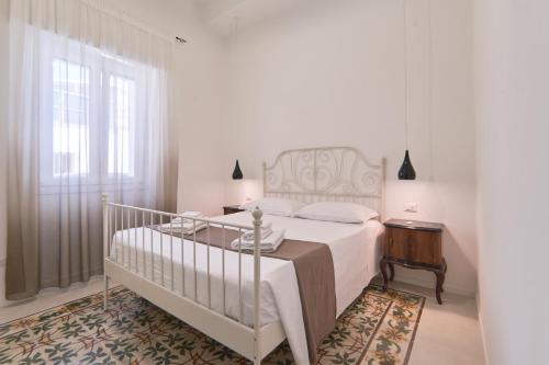 a white bedroom with a bed and a window at Casa dei Nonni in Avetrana