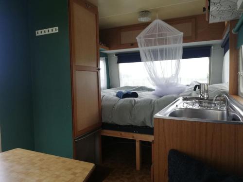 a small room with a bed and a sink at Cute little caravan for 2 in old orchard in Hem