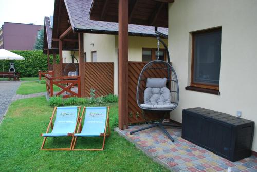 Una silla afuera de una casa con dos carteles. en Kameleon Dźwirzyno, en Dźwirzyno