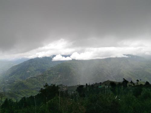 a view of a mountain range with clouds in the sky at Rai Desh Cottages in Shimla