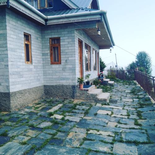 a house with a stone walkway in front of it at Rai Desh Cottages in Shimla