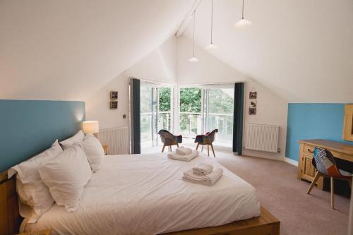 a bedroom with a bed with two chairs and a desk at Trewhiddle Retreat V10 by Together Travel - Luxury 4-Bedroom Villa in St Austell
