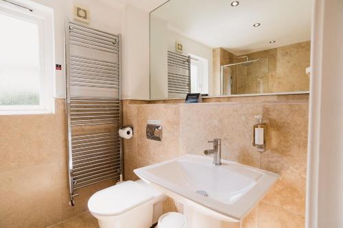 a bathroom with a sink and a toilet and a mirror at Trewhiddle Retreat V10 by Together Travel - Luxury 4-Bedroom Villa in St Austell