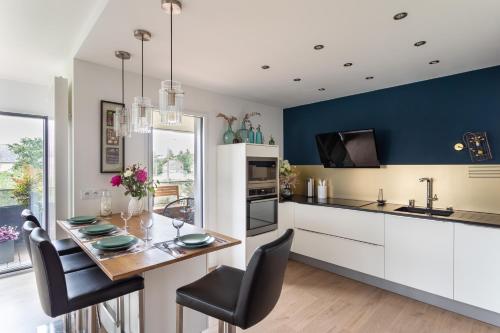 une cuisine avec une table à manger et une cuisine aux murs bleus dans l'établissement Le Canal - Appt avec balcon - Vue dégagée en bord de Vilaine, à Rennes