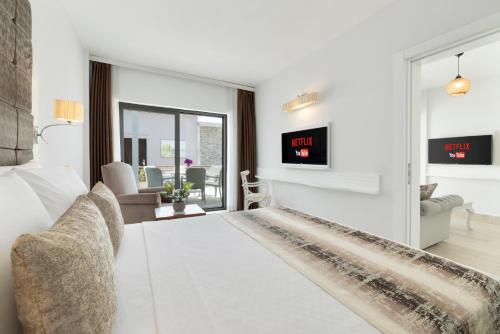 a white bedroom with a large bed and a living room at Elite Hotel Yalıkavak in Yalıkavak