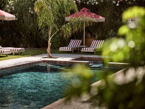 a swimming pool with two chairs and an umbrella at Anemelia Retreat in Laganas