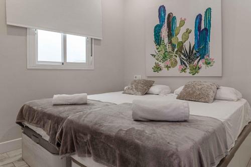 2 camas en un dormitorio con una pintura en la pared en Apartamentos Recaredo 7 , 2ª planta en Sevilla